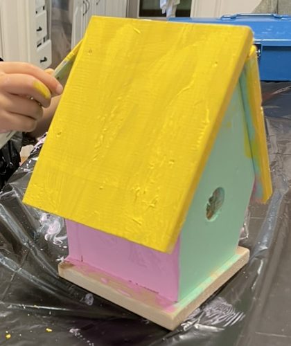 Olive's first Chickadee Birdhouse prototype: a yellow roof, pink front and mint-green side on a natural wood base